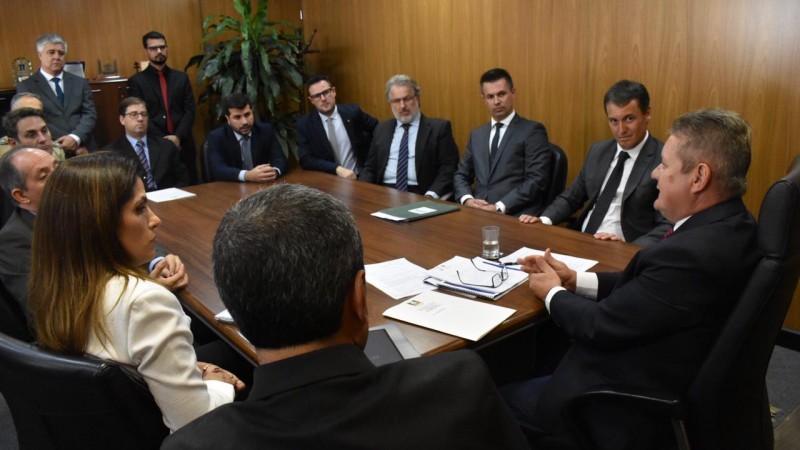 Ranolfo Vieira Júnior, sentado em frente à cabeceira de uma grande mesa, se reúne com 17 autoridades de comitiva do município de Passo Fundo.