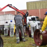 Homens da SSP levam sucata automotiva recolhida em ferro velho de Caxias do Sul. Ao fundo, caminhão com caçamba para coleta.