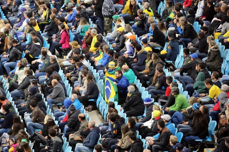 Arquibancada lotada na Arena. Em destaque, homem que segura bandeira no Brasil.