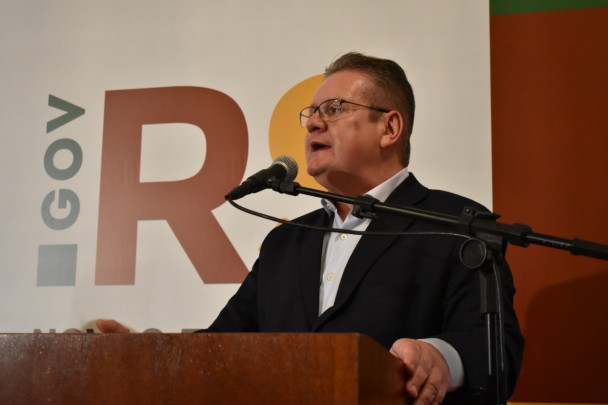 Vice-governador discursa em púlpito com microfone. Ao fundo, marca do governo.