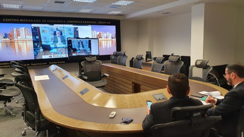 Em primeiro plano, o Secretário Adjunto da SSP, Marcelo Frota, sentado na ponta da mesa de reunião. Em segundo plano, a tela pela qual foi realizada a videoconferência. Nela, está, ao centro, o Secretário da SSP, Ranolfo Vieira Jr..