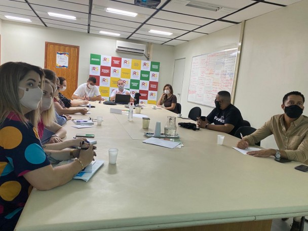 Muitas pessoas em volta de uma mesa participando de uma reunião