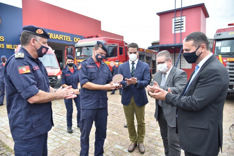 Comandante-geral do CBMRS, cel. Bonfanti, subcomandante, Cel. Ruzicki, que segura uma escultura, governador Eduardo Leite, vice-governador Ranolfo Vieria Júnior, e secretário adjunto da SSP, cel. Frota, batem palma em homenagem a Ruzicki que vai à reserva