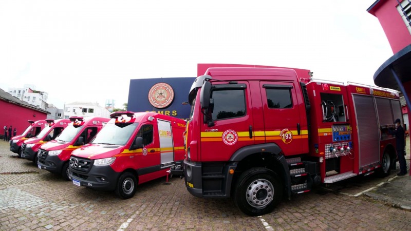 Quatro ambulâncias de resgate estacionadas lado a lado e um caminhão de combate à incêndio diante do prédio do comando-geral do CBMRS, na Capital.