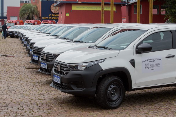 Fila de vários veículos Fiat Strada brancos estacionados lado a lado.