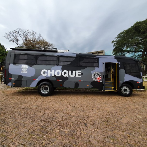 Lateral de um dos ônibus recebidos, revestido de estampa camuflada com tons de azul claro, azul escuro e cinza. Sua porta está aberta e leva escrito em letras grandes a palavra "choque" na metade da lataria.