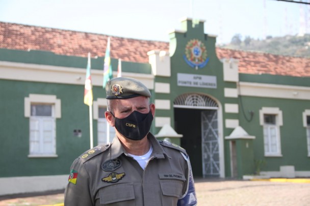 tenente coronel da BM fardado e de máscara, ao fundo o prédio da APM
