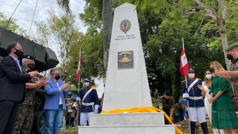 Ranolfo, militares e familiares do general Miotto, em pé, aplaudem, em torno do obelisco com uma placa e brasão do Exército inaugurado em homenagem ao finado ex-comandante do CMS.