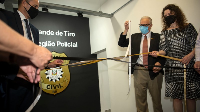 O subchefe da PC, delegado Fábio Motta Lopes, e a diretora-geral do IGP, perita criminal Heloísa Helena Kuser, desatando o laço de inauguração do estande de tiro.
