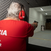 Agente da Polícia Civil mirando, prestes a atirar no alvo do estande.