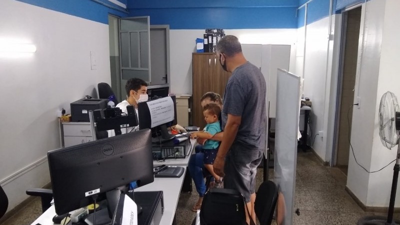 A imagem mostra um posto de atendimento do IGP, com um atendente prestando serviço a um família.