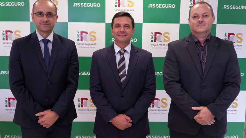 Em pé, de terno e gravata, lado a lado, da esquerda para direita, o delegado Fábio Motta Lopes, o coronel Vanius Cesar Santarosa e o delegado Vladimir Urach.
