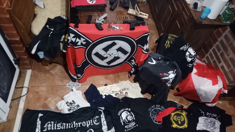 Foto mostra materiais de apologia ao neonazismo, como bandeiras e camisetas, além de armas.