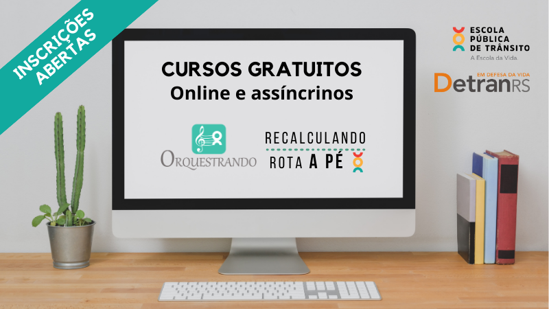 Foto horizontal colorida mostra um computador de mesa com livros do lado direito e uma planta a esquerda