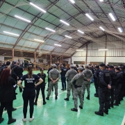 Foto mostra policiais civis e militares em ginásio durante briefing da operação. 
