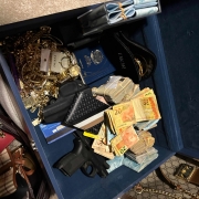 A foto mostra dinheiro, arma e jóias 