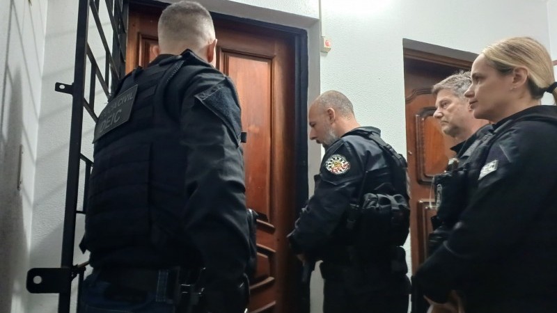 A foto mostra agentes cumprindo mandatos de prisão e apreensão