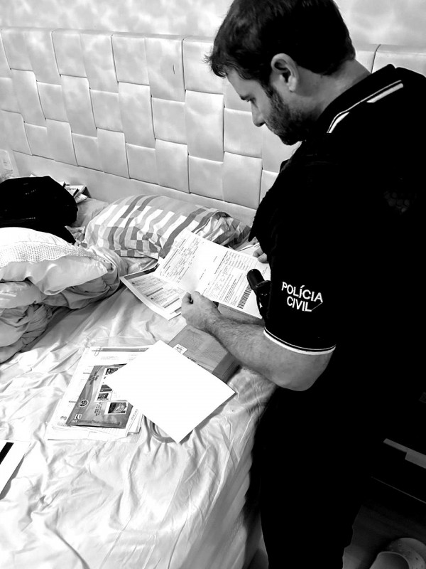 Policial civil analisa documentos encontrados em diligência