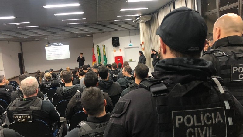 Cerca de 30 agentes da Polícia Civil fardados se reúnem em um auditório para coordenarem a operação