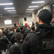 Cerca de 30 agentes da Polícia Civil fardados se reúnem em um auditório para coordenarem a operação