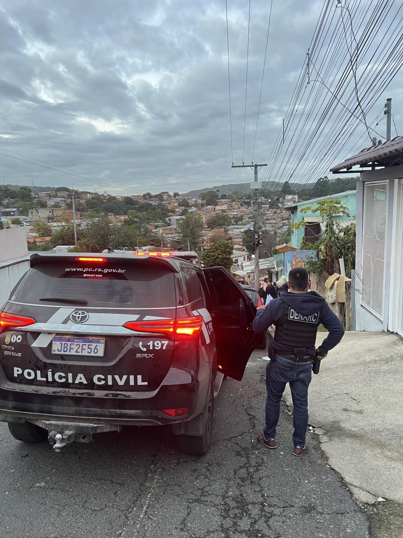 Policiais civis fardados descem de carro em comunidade de Gravataí (RS).