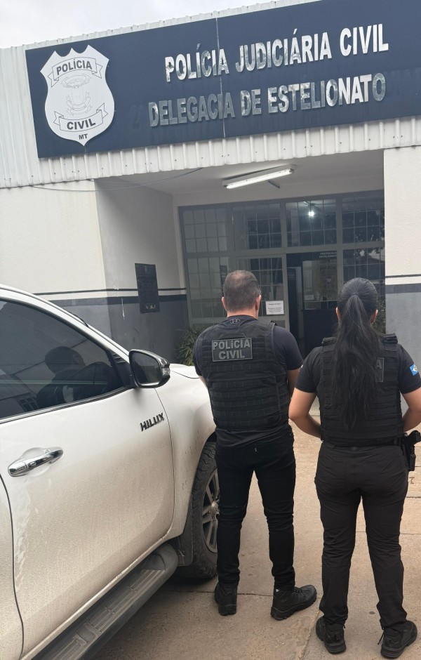 A imagem traz agentes da Polícia Civil fardados em frente a uma delegacia da polícia judiciária do Mato Grosso