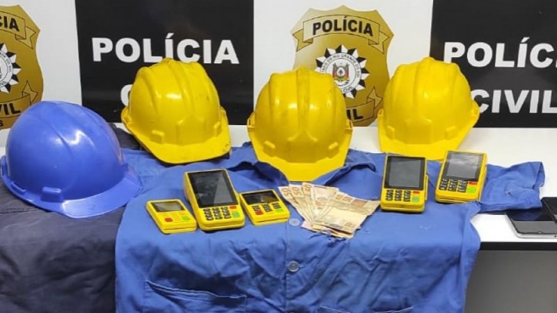 Três capacetes amarelos e um azul, uniformes e máquinas de cartão apreendidas durante a ação policial