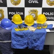 Três capacetes amarelos e um azul, uniformes e máquinas de cartão apreendidas durante a ação policial