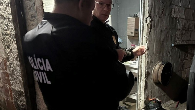 A imagem mostra dois agentes da polícia civil durante o cumprimento dos mandatos da Operação Medici Umbra