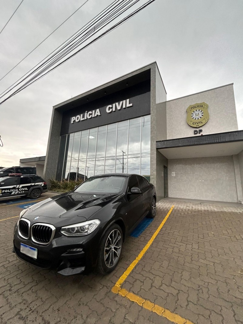 Um automóvel preto de luxo apreendido está estacionado na frente da delegacia de Polícia de Caxias do Sul.