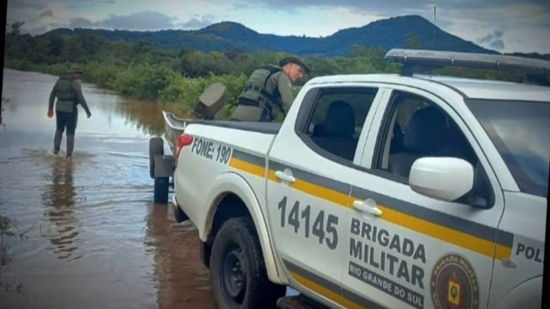 A imagem mostra uma viatura da Brigada Militar em uma região alagada do Estado. Há também dois agentes da Brigada Militar que estão participando dos resgates