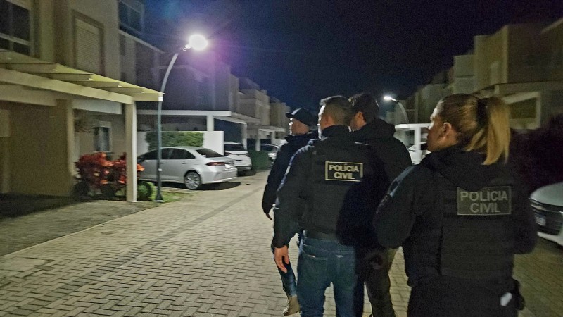 Quatro policiais, três homens e uma mulher, se dirigem ao local da apreensão, um condomínio de casas.