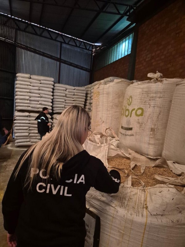 Uma policial civil analisa os sacos de sementes em um armazém.