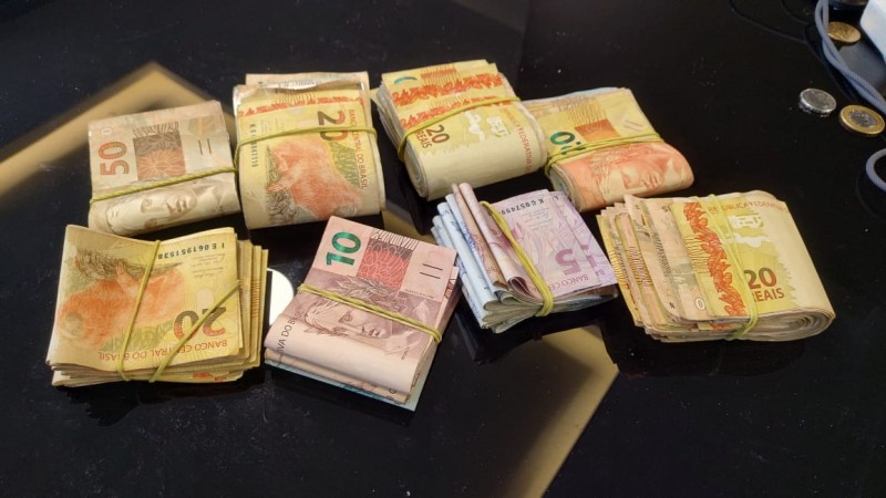 grande quantitade de dinheiro em esp&eacute;cie sobre uma mesa de vidro