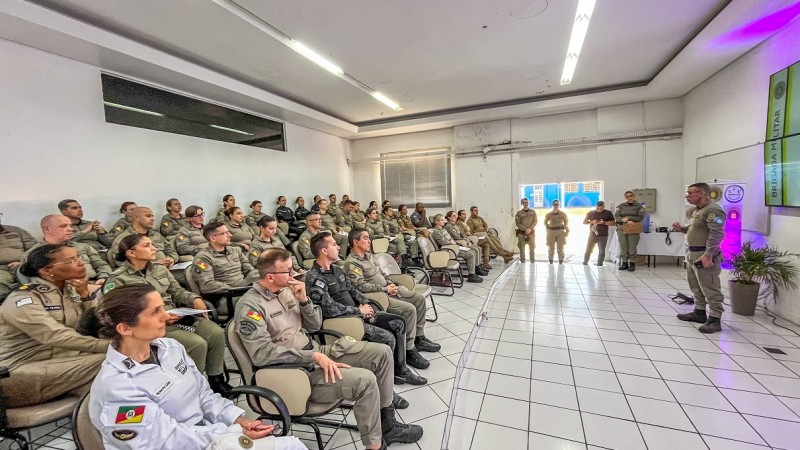 Uma sala de aula est&aacute; repleta de formandos do Curso. &Agrave; frente e em p&eacute;, fala o diretor do Departamento de Ensino. H&aacute; luzes cor-de-rosa decorando o ambiente em alus&atilde;o ao tema da prote&ccedil;&atilde;o &agrave;s mulheres.