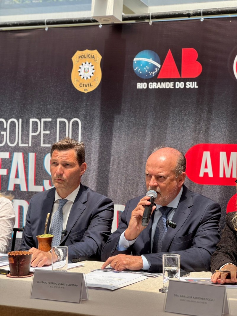 dois homens de terno e gravata azuis, um deles segura o microfone