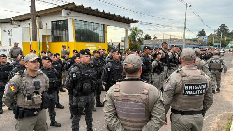 A imagem mostra servidores da Brigada Militar fardados, em posi&ccedil;&atilde;o de descanso, em frente ao Grupo Rodovi&aacute;rio de Viam&atilde;o