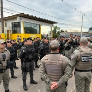 A imagem mostra servidores da Brigada Militar fardados, em posi&ccedil;&atilde;o de descanso, em frente ao Grupo Rodovi&aacute;rio de Viam&atilde;o