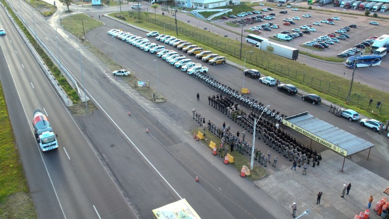 A imagem a&eacute;rea mostra servidores da Brigada Militar perfilados durante o lan&ccedil;amento da opera&ccedil;&atilde;o. Tamb&eacute;m &eacute; poss&iacute;vel ver viaturas estacionadas e ve&iacute;culos trafegando na estrada