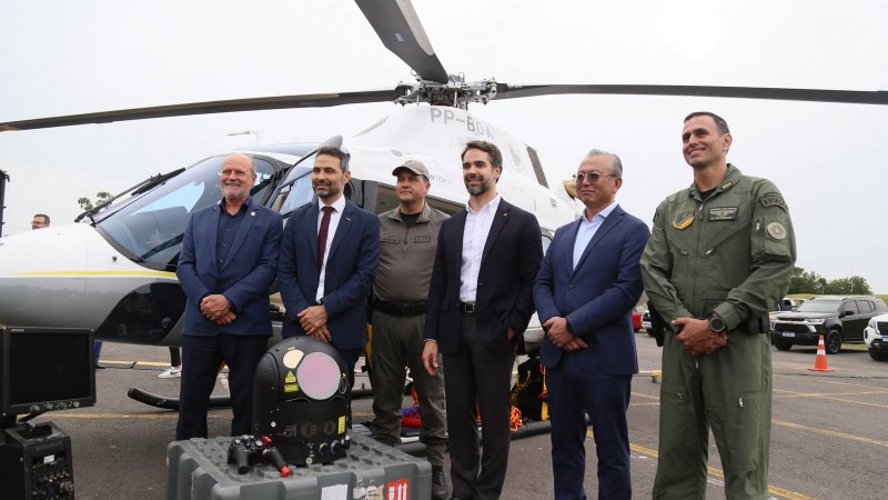 Foto mostra o governador Eduardo Leite em frente ao helic&oacute;ptero com outras autoridades e militares.