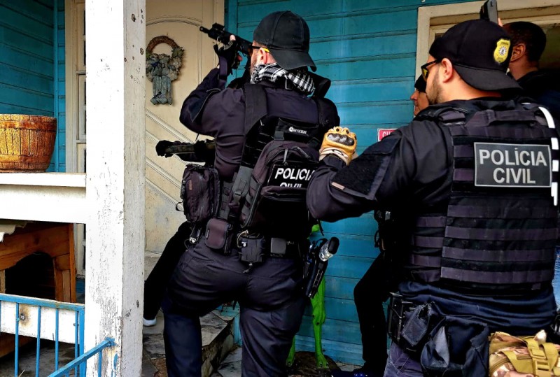 Na imagem dois policiais se preparam para entrar em uma casa